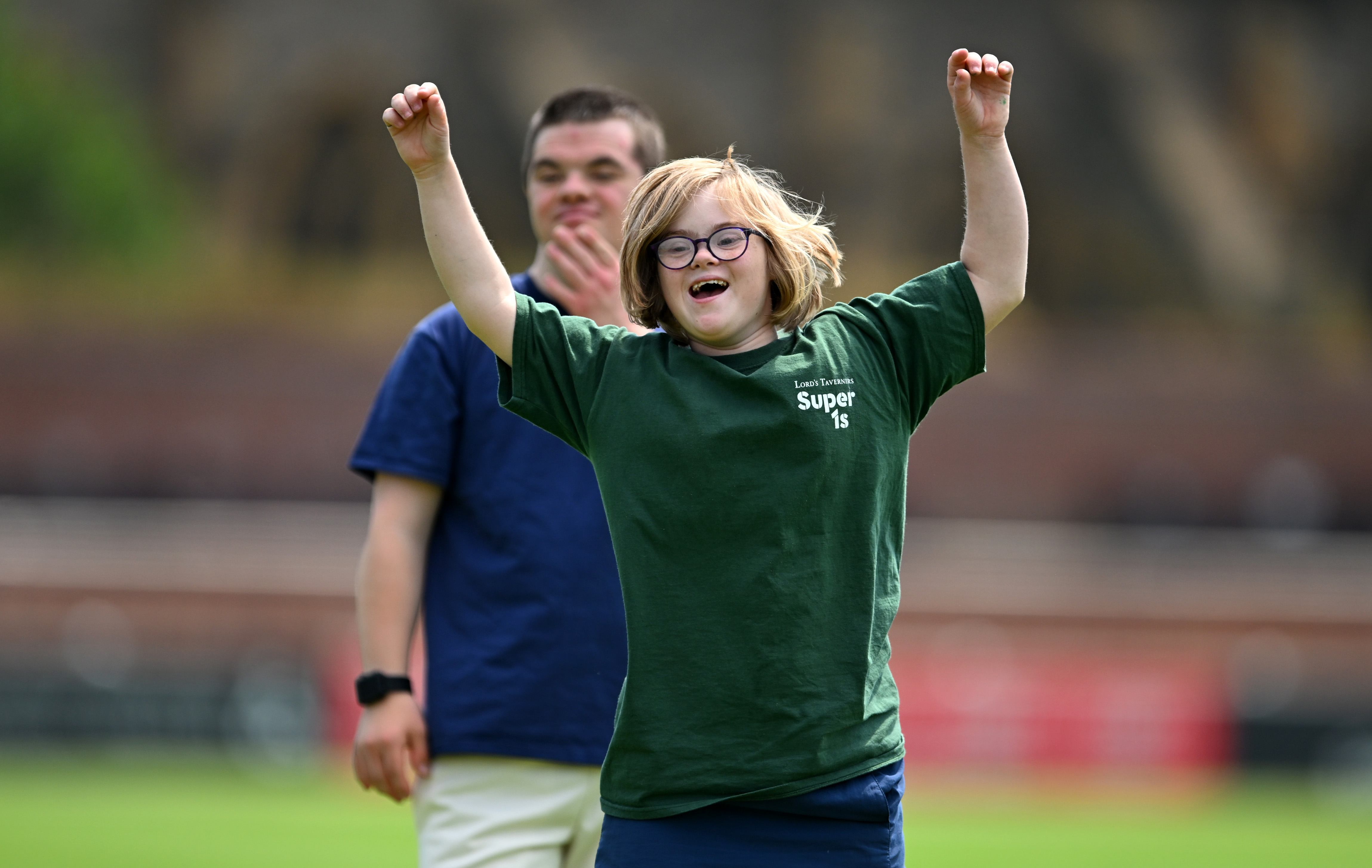 A group of diverse young people celebrating a victory on a cricket pitch.
